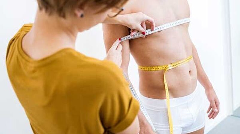 Apparel Engineer measuring torso of man for size table development