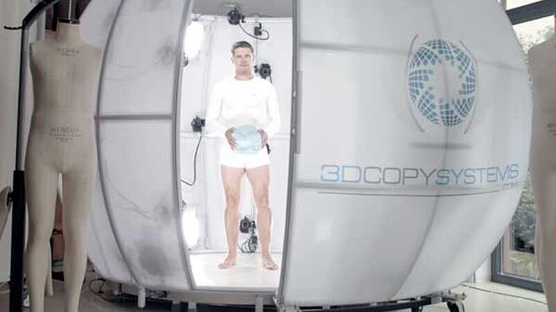 Man holding ball and standing inside 4D scanner at Hohenstein Digital Fitting Lab